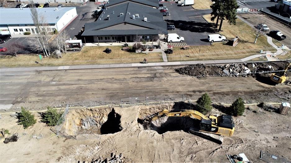 An aerial photo overlooking work crews using excavators to continue demolition work to curbs & sidewalks and excavation in preparation for installing drywells and sedimentation maintenance holes.