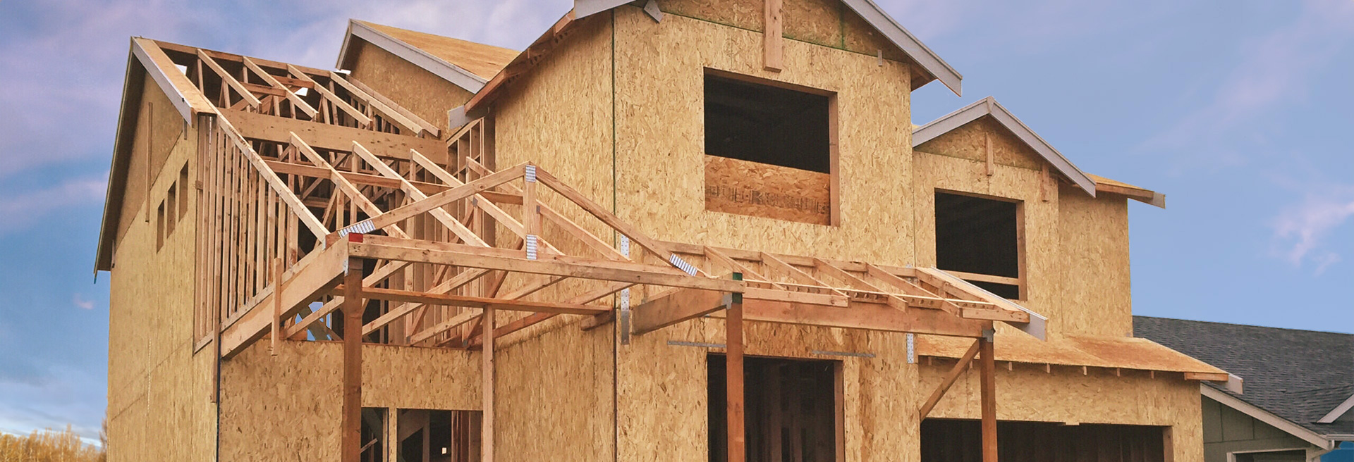 Image of a house under construction, two-stories, party cloudy skies in the background