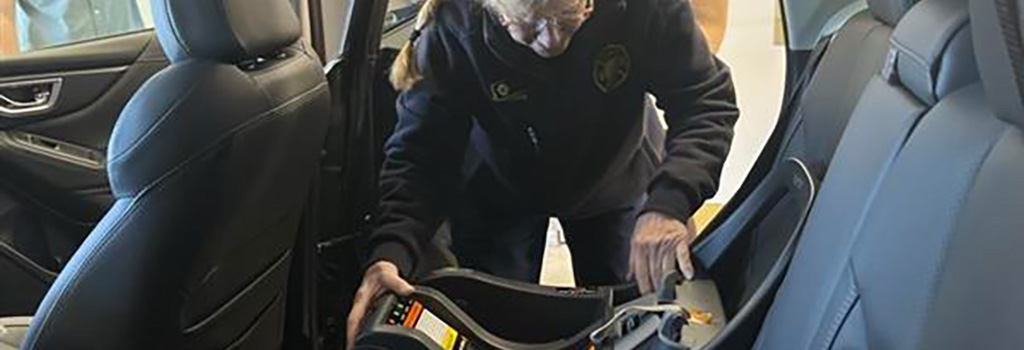 Firefighter strapping in a cat seat to the back seat of a vehicle.