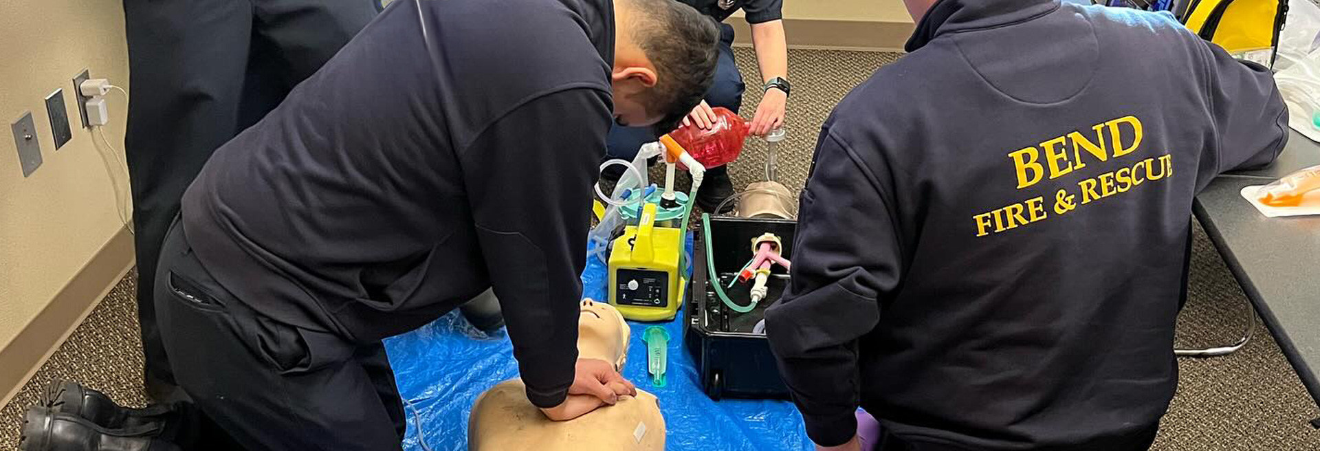Fire & Rescue personnel practicing CPR on a test mannequin.