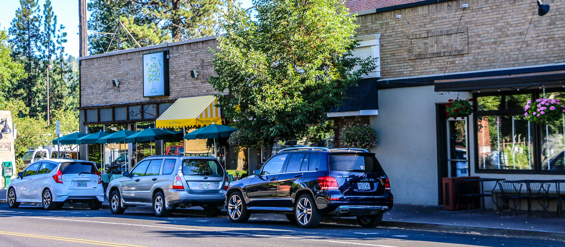 Cars parked on the street along businesses in Downtown Bend.