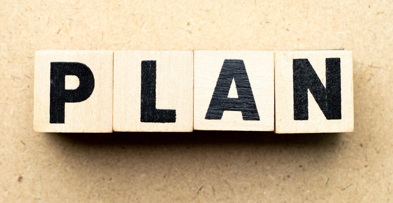 Blocks with the letters spelling out the word plan in black, brown background.
