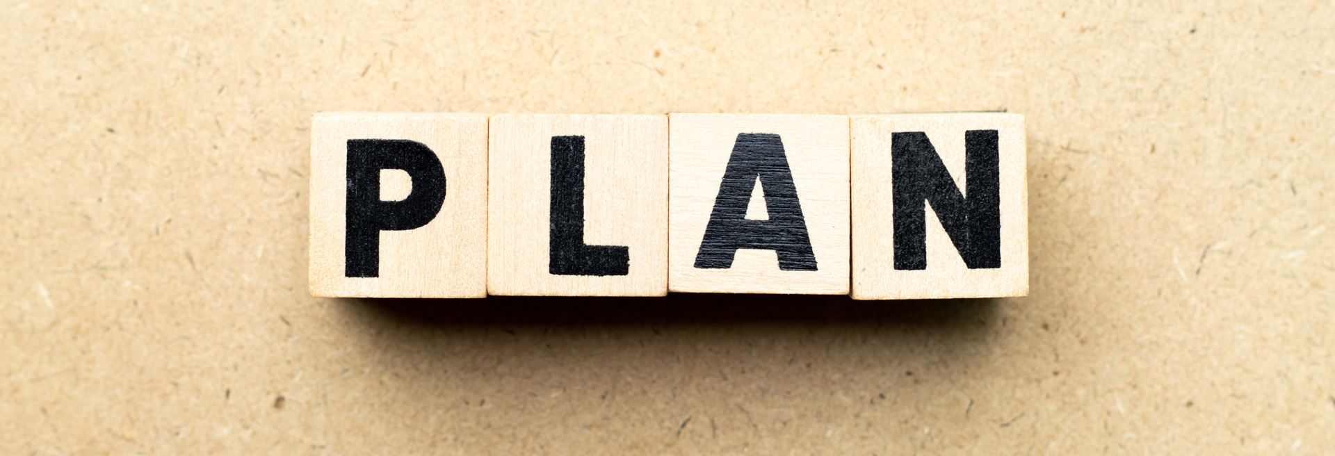 Blocks with the letters spelling out the word plan in black, brown background.