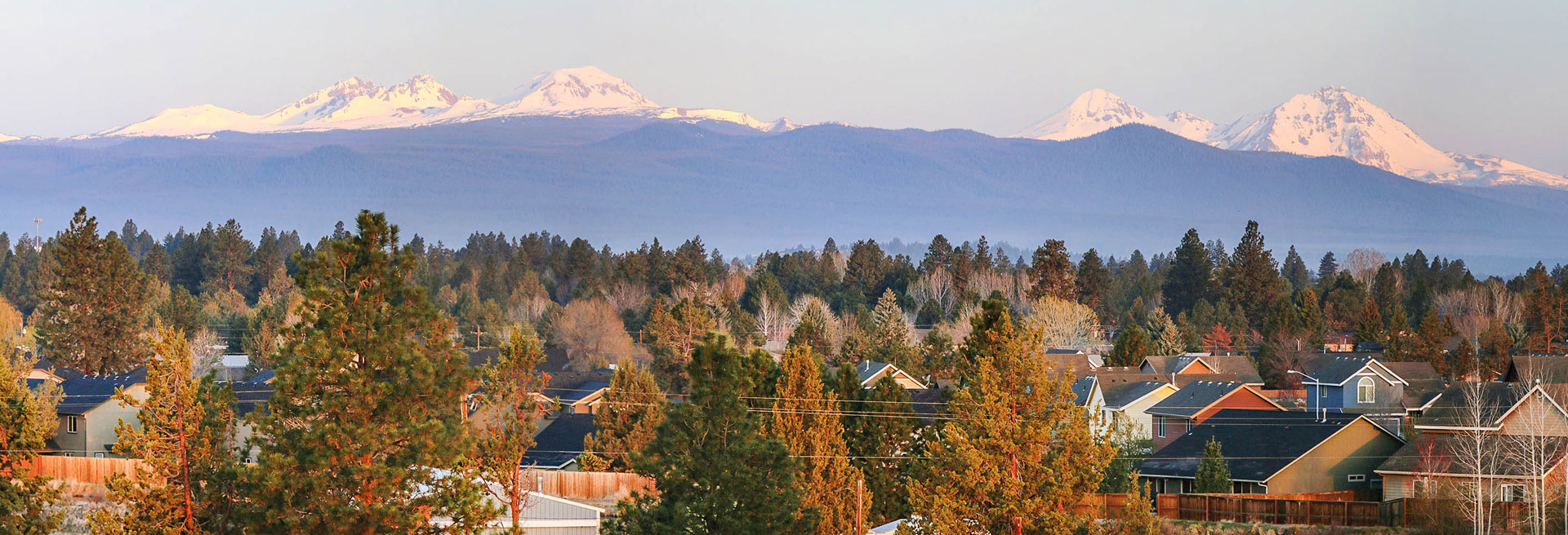 Shot of Bend from a bird's eye view. Three Sisters mountains in the background. Blue skies.