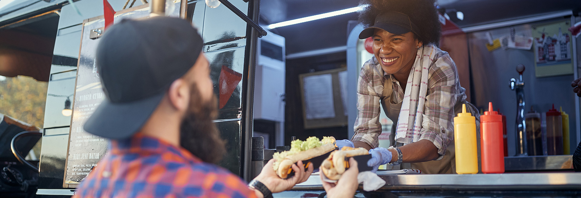 Peron serving food to a customer through the window of a Food Truck.