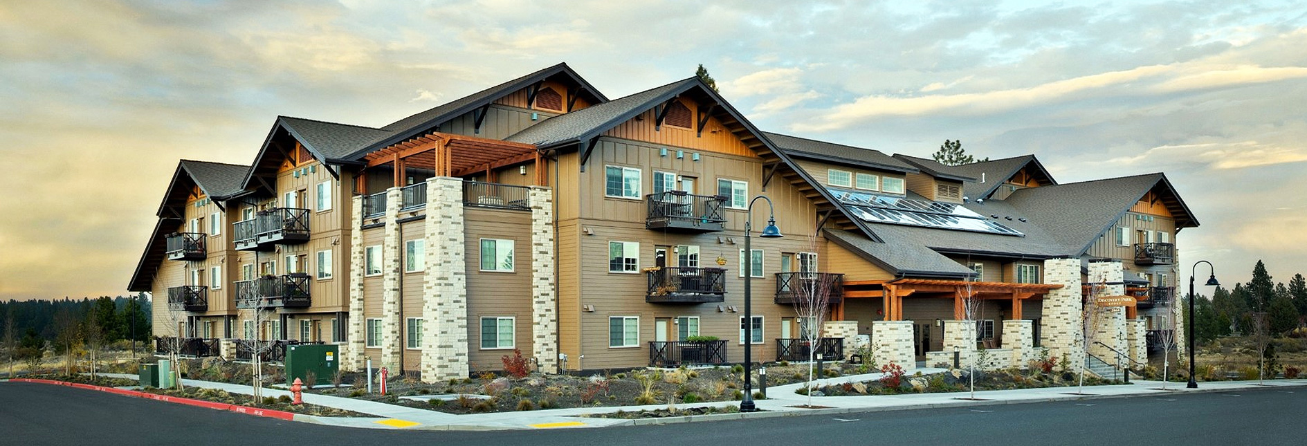 Apartment buildings from the outside. Brown and red colors on the buildings, landscaped with grass and sidewalks.