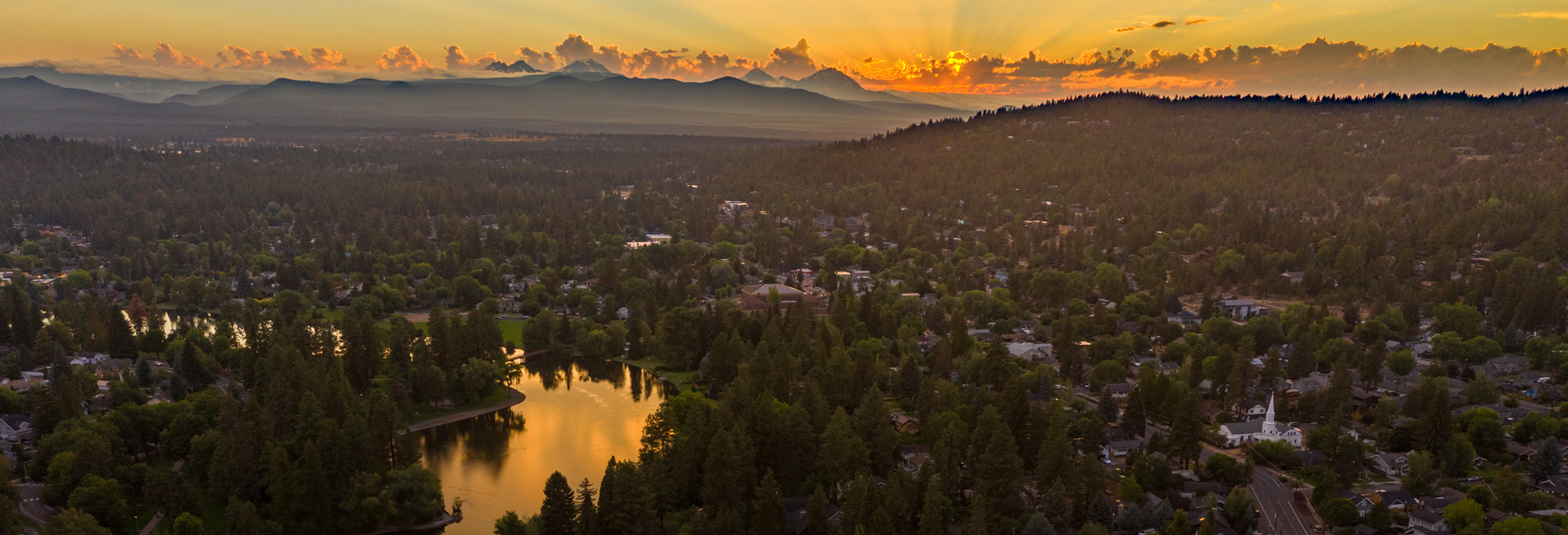 Sunset over Bend, mountains in the midground, city with Deschutes River flowing through in the foreground