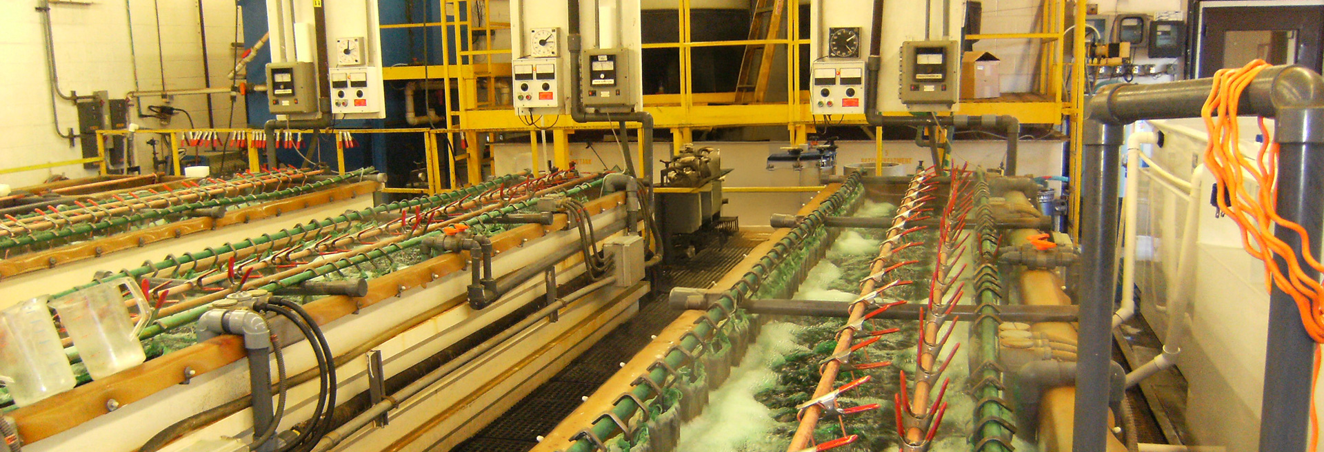 Pre-treatment equipment processing fluids. Hoses, camps, basins, Yellow walkways surround the equipment.