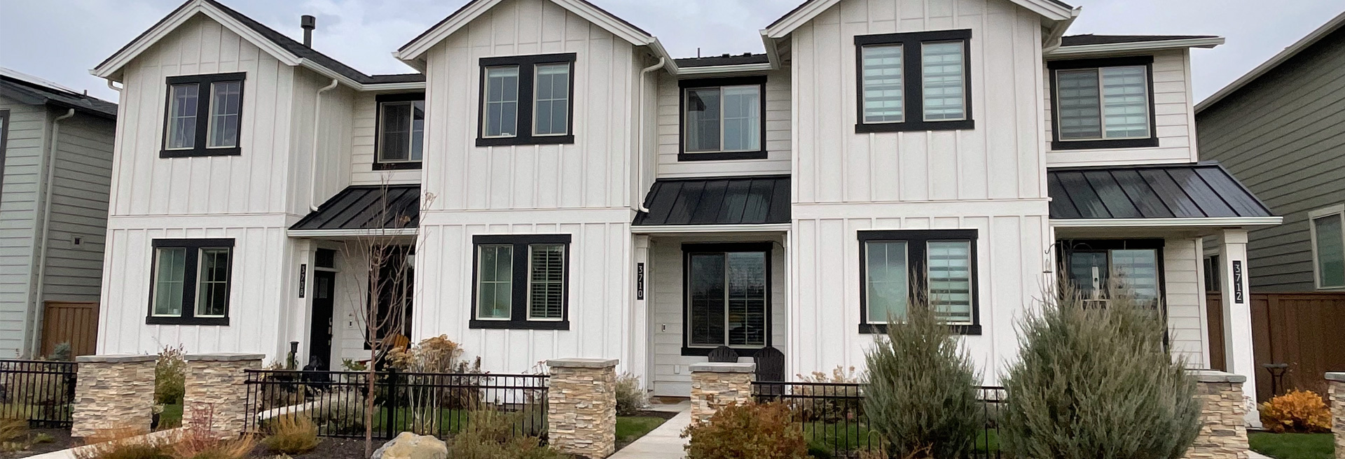 Picture of a white quad-plex. Two stories, windows with dark trim.