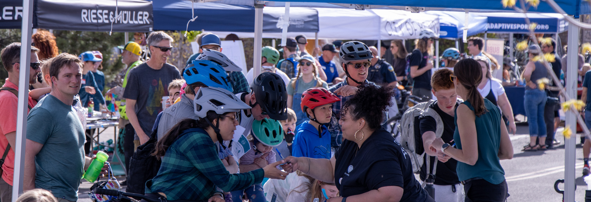 People receiving assistance at a booth during a Community Gathering. Men, women and children of diverse backgrounds all represented.