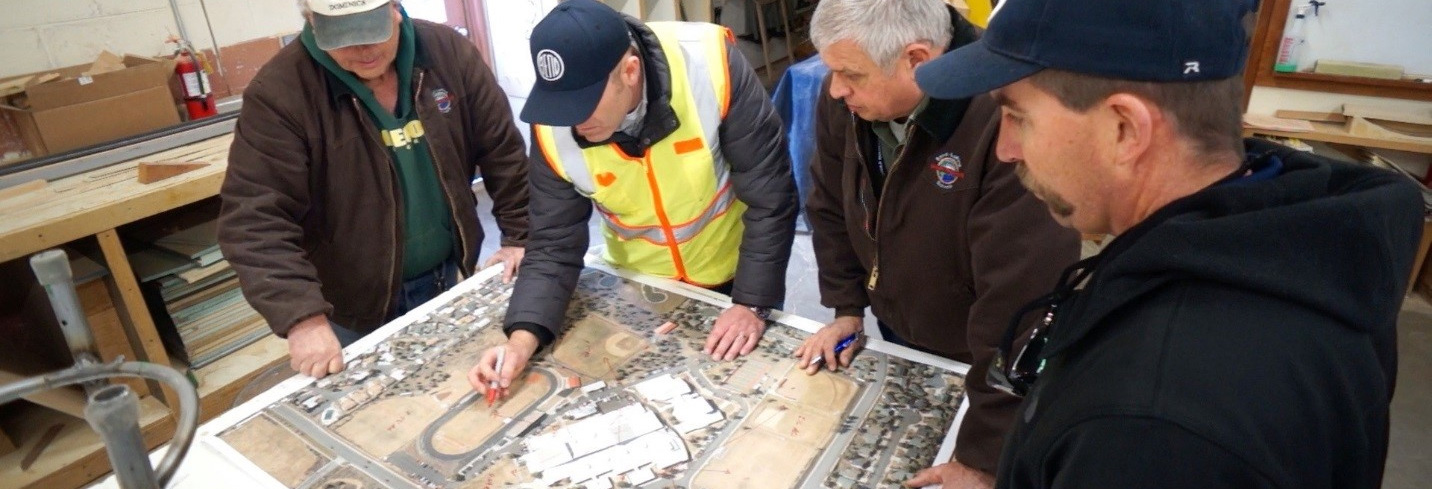 Four contractors looking down at landscaping blueprints.
