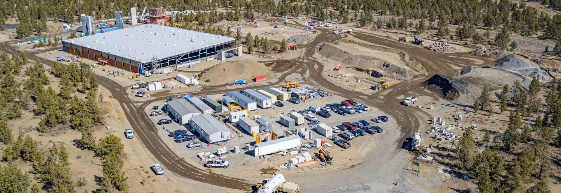 Image of Boyd Acres complex in Juniper Ridge. Under construction. Juniper trees and sagebrush surround the under construction campus.
