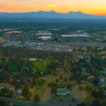 The City of Bend from overhead at sunset. Three Sisters mountains are in the background.