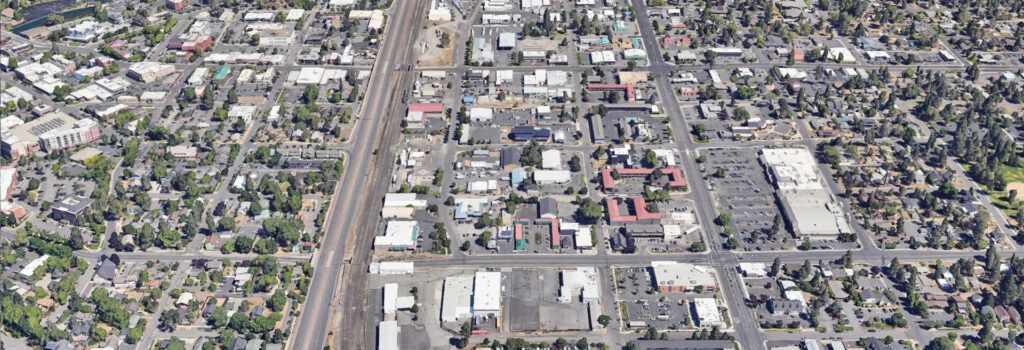 Satellite view of project area. Looking north through Bend, Bend Parkway through the middle, streets and crossings, buildings, and houses shown.