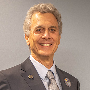 Mike is of fair complexion and has short gray hair.