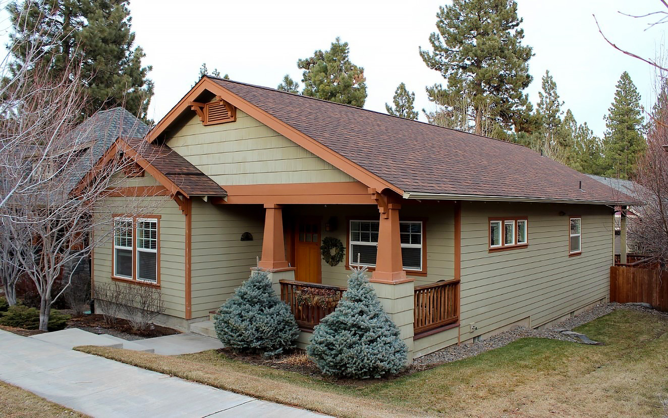 Sage colored ranch-style house, fully landscaped with a sidewalk in front.