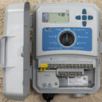 Smart irrigation controller, gray in color, mounted to a tan wall.