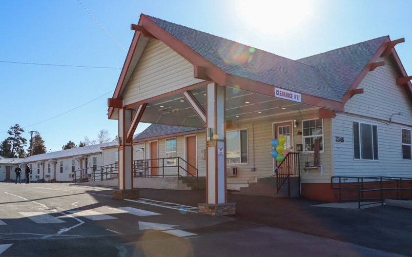 Exterior of the shelter. Tan siding, red trim, windows and doors on the whole building shown.