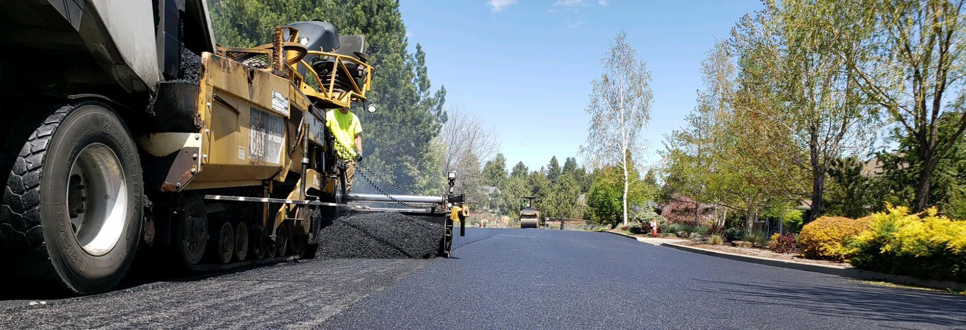 Machine spreading asphalt onto a neighborhood street.