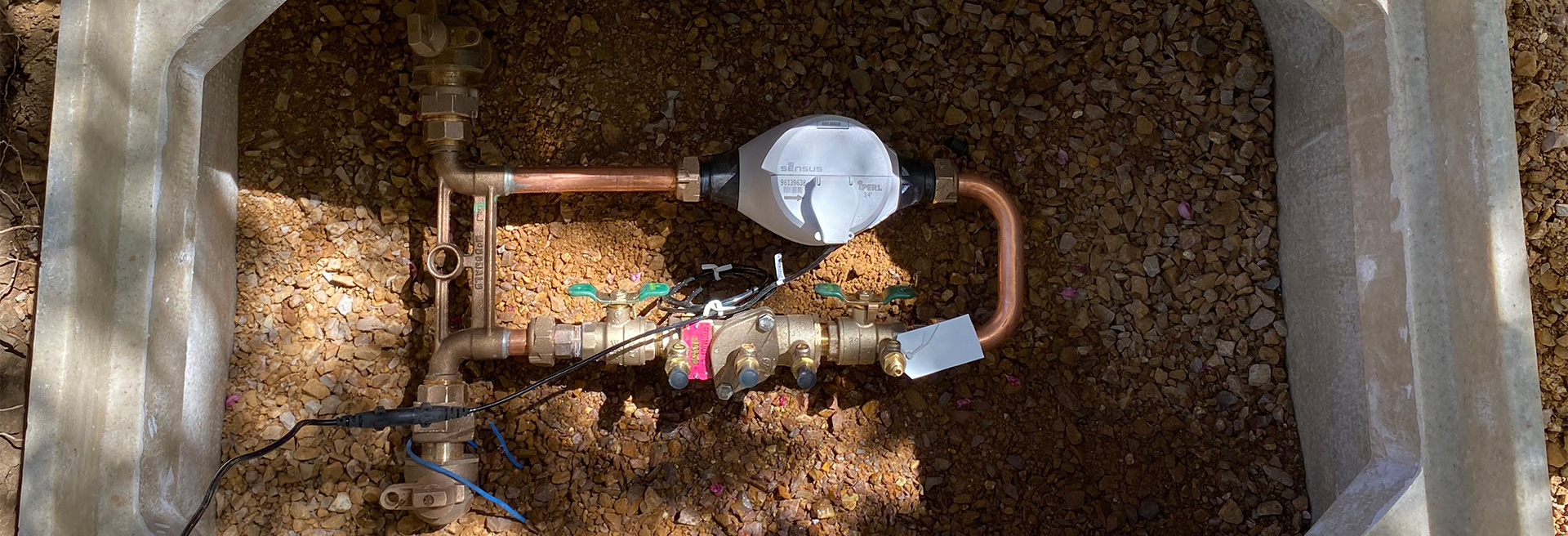 Water Meter inside of a box surrounded by brown earth.