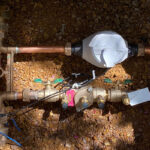 Water Meter inside of a box surrounded by brown earth.