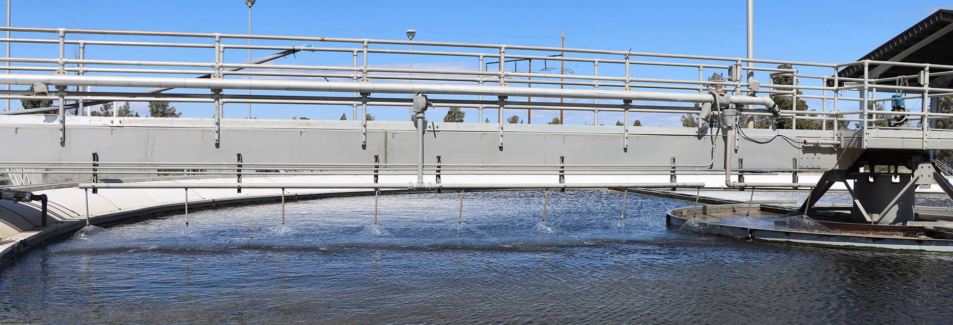 Water Reclamation Facility of water surrounded by equipment. Blue sky in the background.