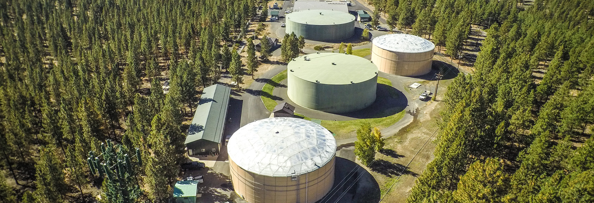 Drone shot or large water tanks, trees surround the tanks.