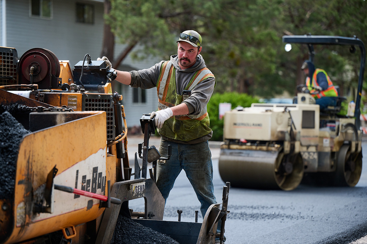 Man riding on a machine that paves streets.