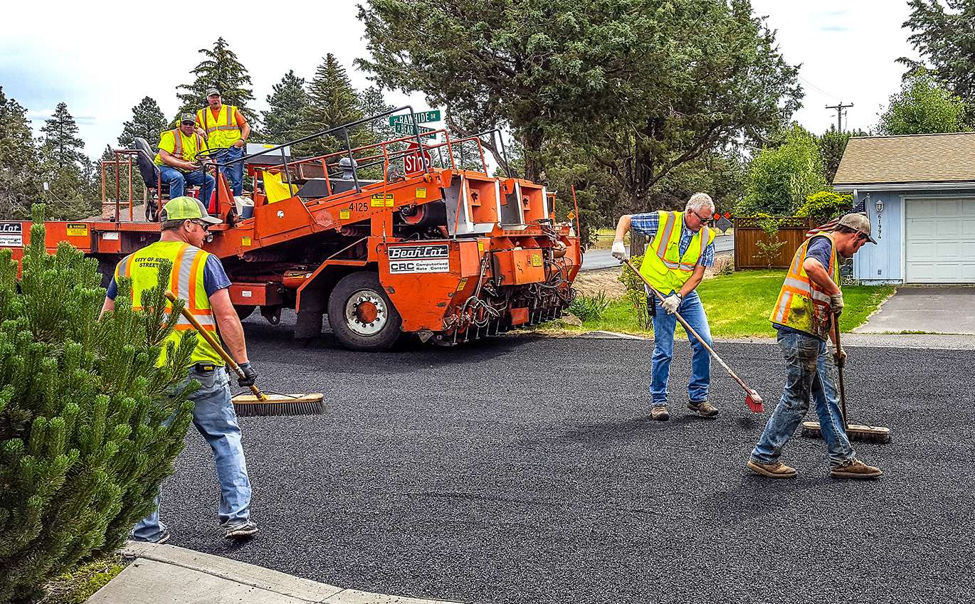 Workers completing asphalt work on a city street.