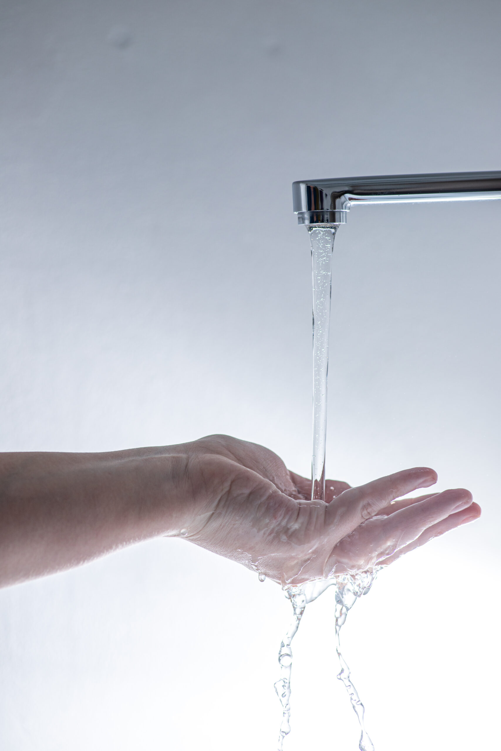 A hand catches water under a running faucet