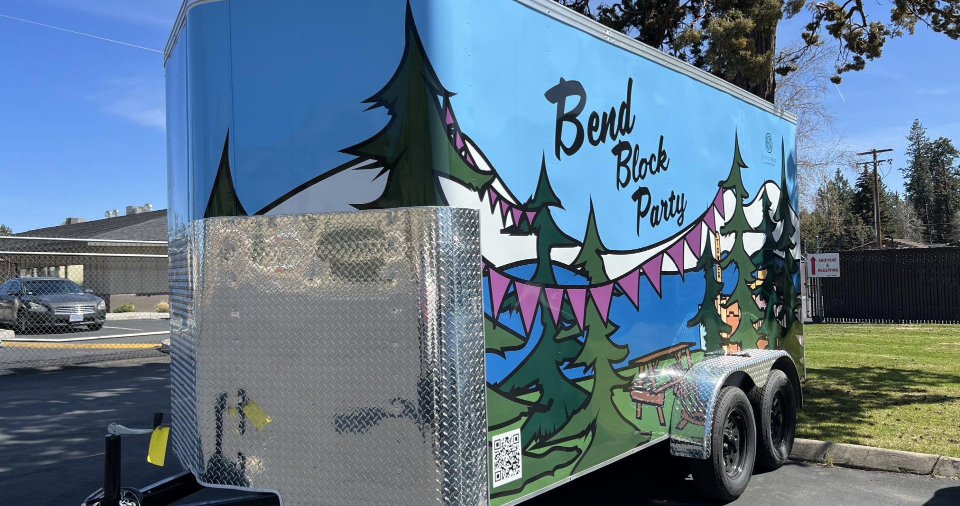 Coloful trailer with 4 wheels sitting outside on a sunny day with blue skies.