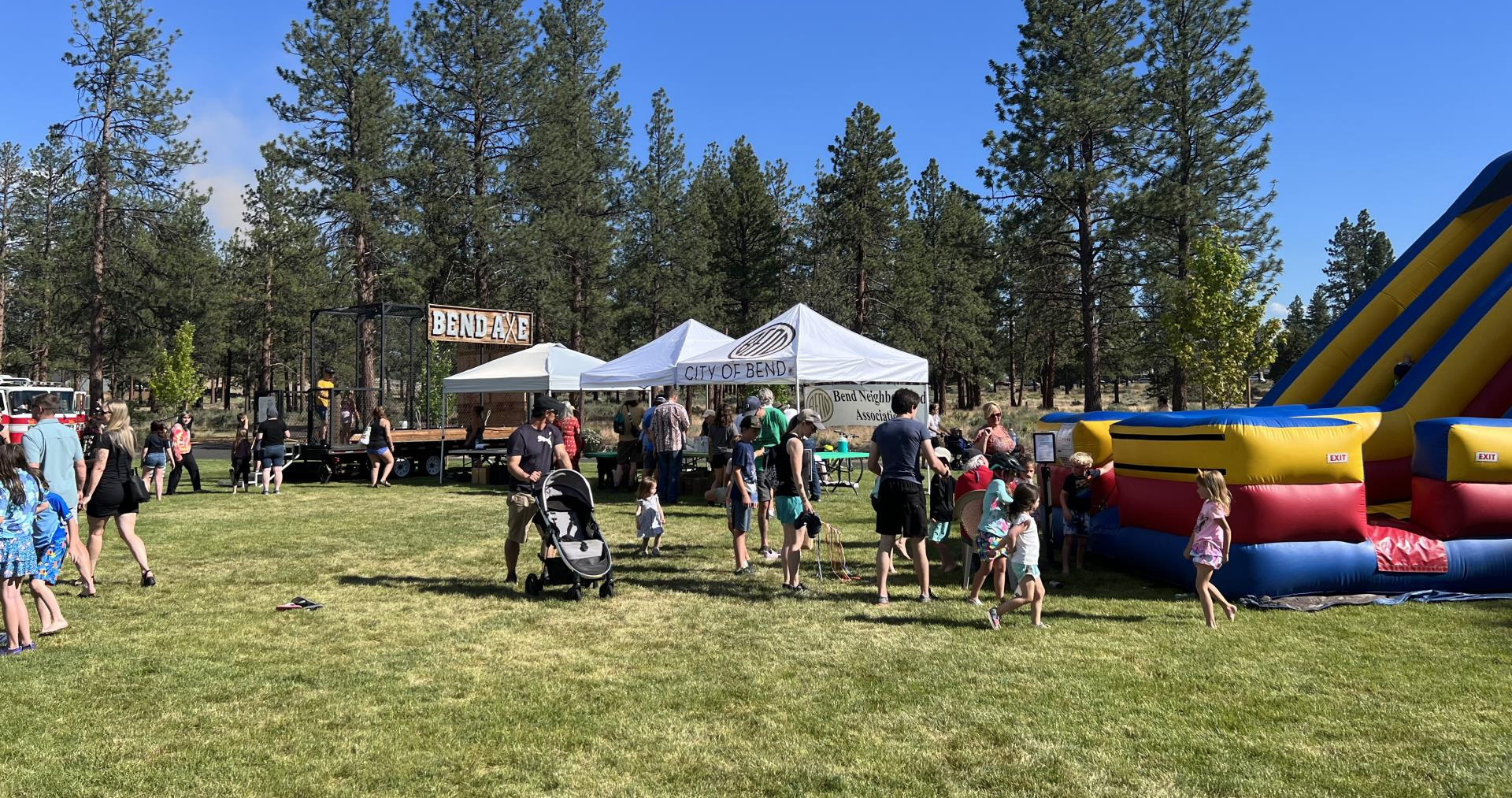 Families expoloring City of Bend information booths in a local park.