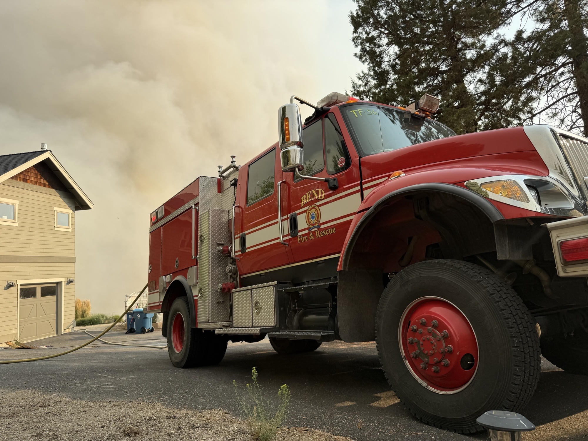 Fire Truck outside of a home with smoke in the background.