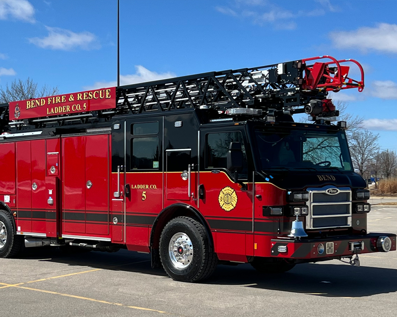 Large fire engine with a ladder on top of it sitting on a concrete surface.