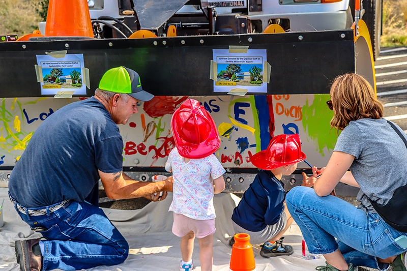 People and children painting the shovel on a plow.