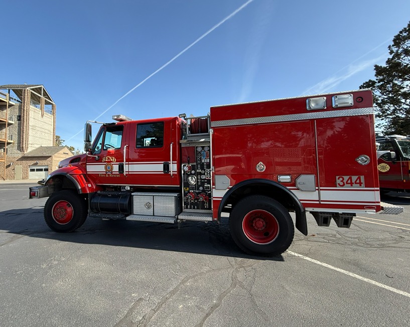 Red fire engine sitting in a parking lot.