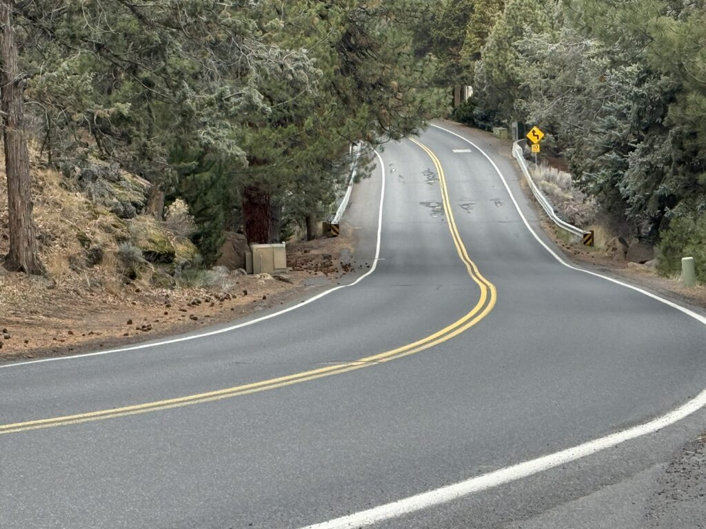 Picture of a two-lane road winding through a neighborhood and over a bridge.