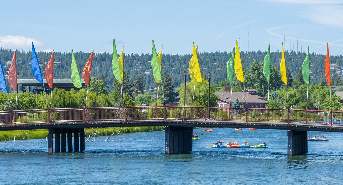 Bridge over a river with colorful flags attached to it.