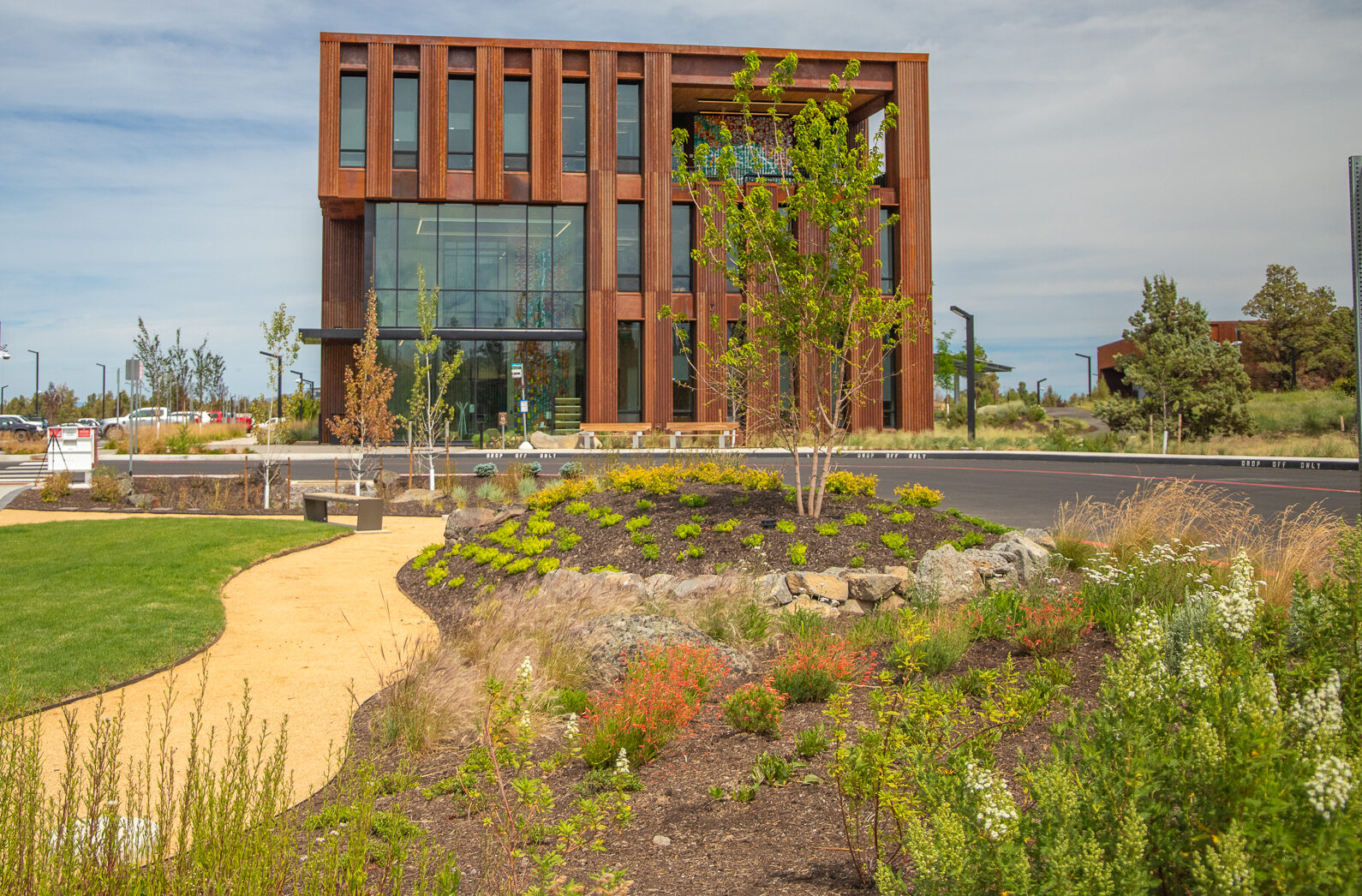 rust colored metal building in background with garden plantings and dirt path