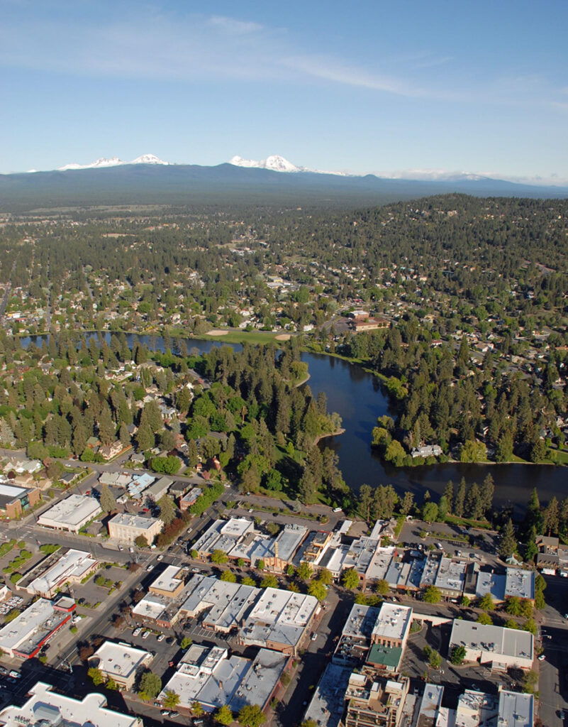 Preciosa imagen de la ciudad de Bend. Las montañas Cascade al fondo. Cielo azul. El río Deschutes discurre por el centro de la ciudad.