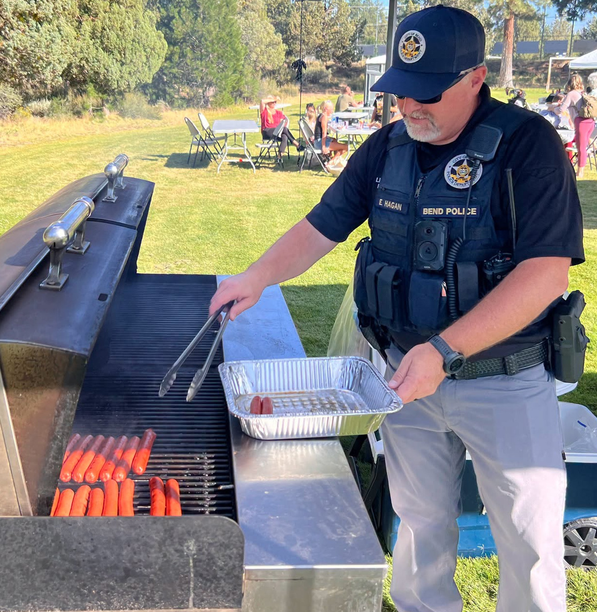 Police Officer grilling hot dogs on a BBQ.