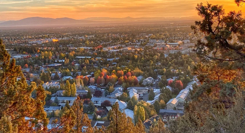 City of Bend at sunrise with autumn colors and mountains in the distance.