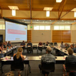 People sitting around a group of tables in a meeting.