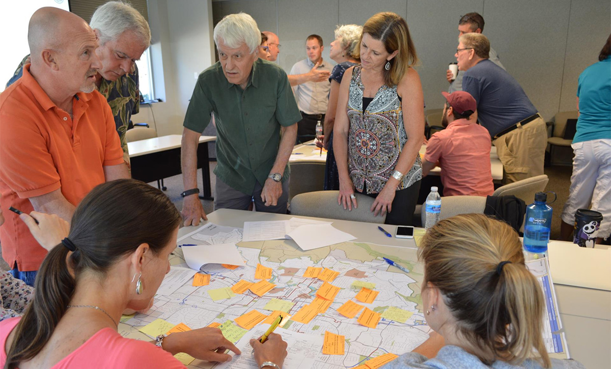 Group of people surrounding a table looking at documents.