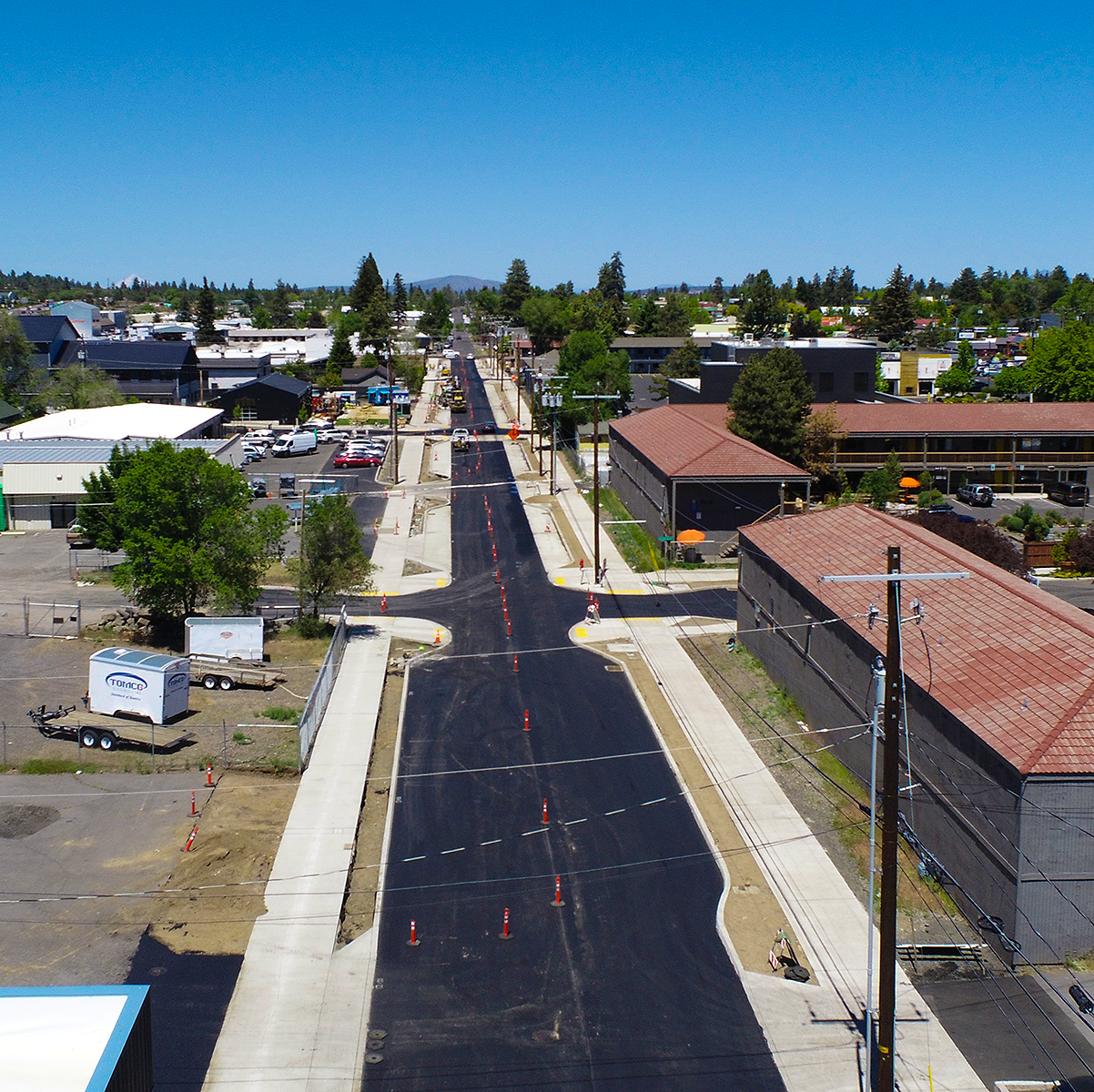 Freshly paved city street from overhead. Businesses surround the street.